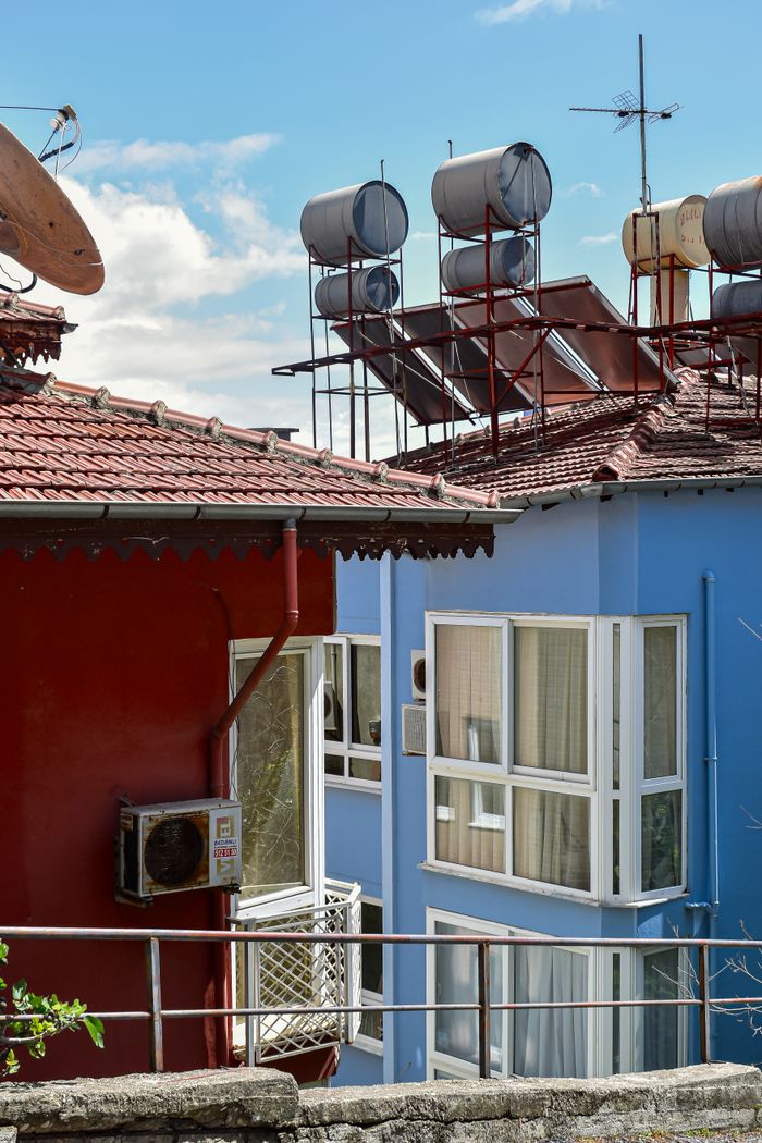 our-services-02 Colorful rooftops with solar water heaters in sunny urban setting. Ideal for energy or architecture themes.